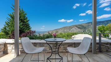 Una terrazza con tavolo e due sedie, affacciata su un paesaggio montuoso.