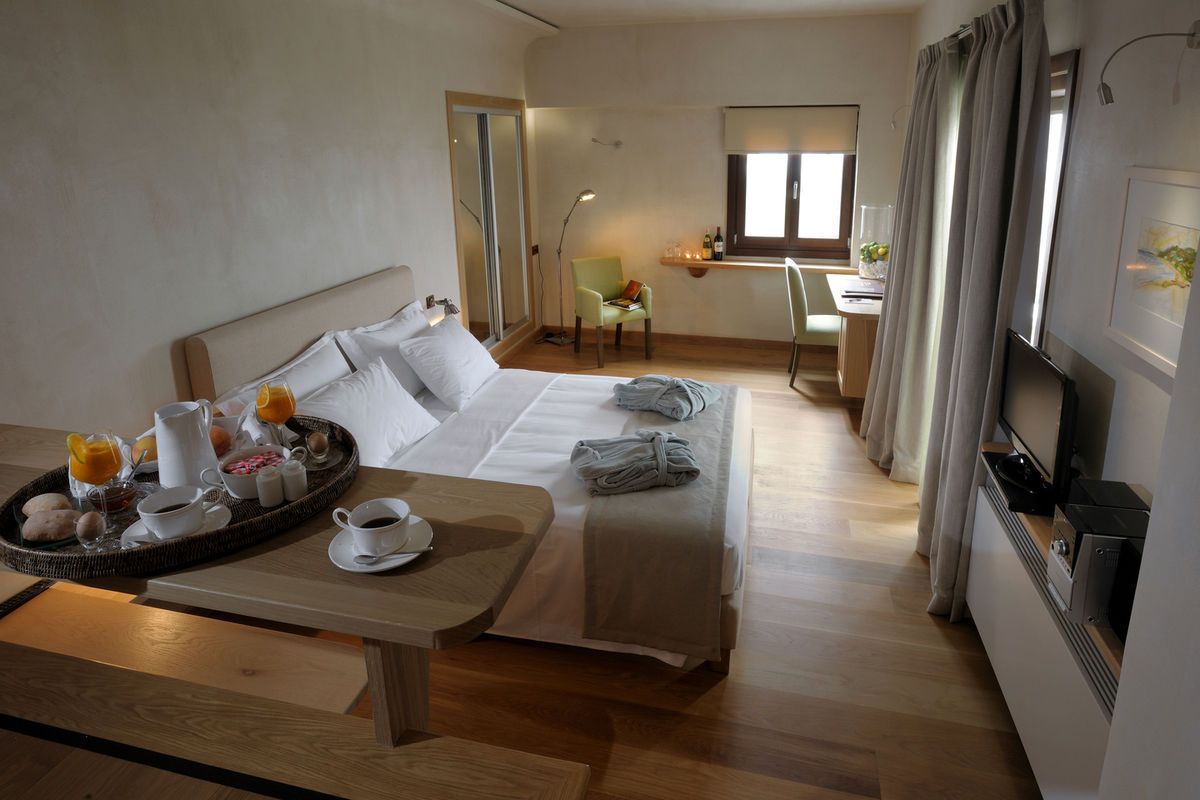 Een hotelkamer met een bed, een ontbijttafel, een bureau, een stoel en een televisie.