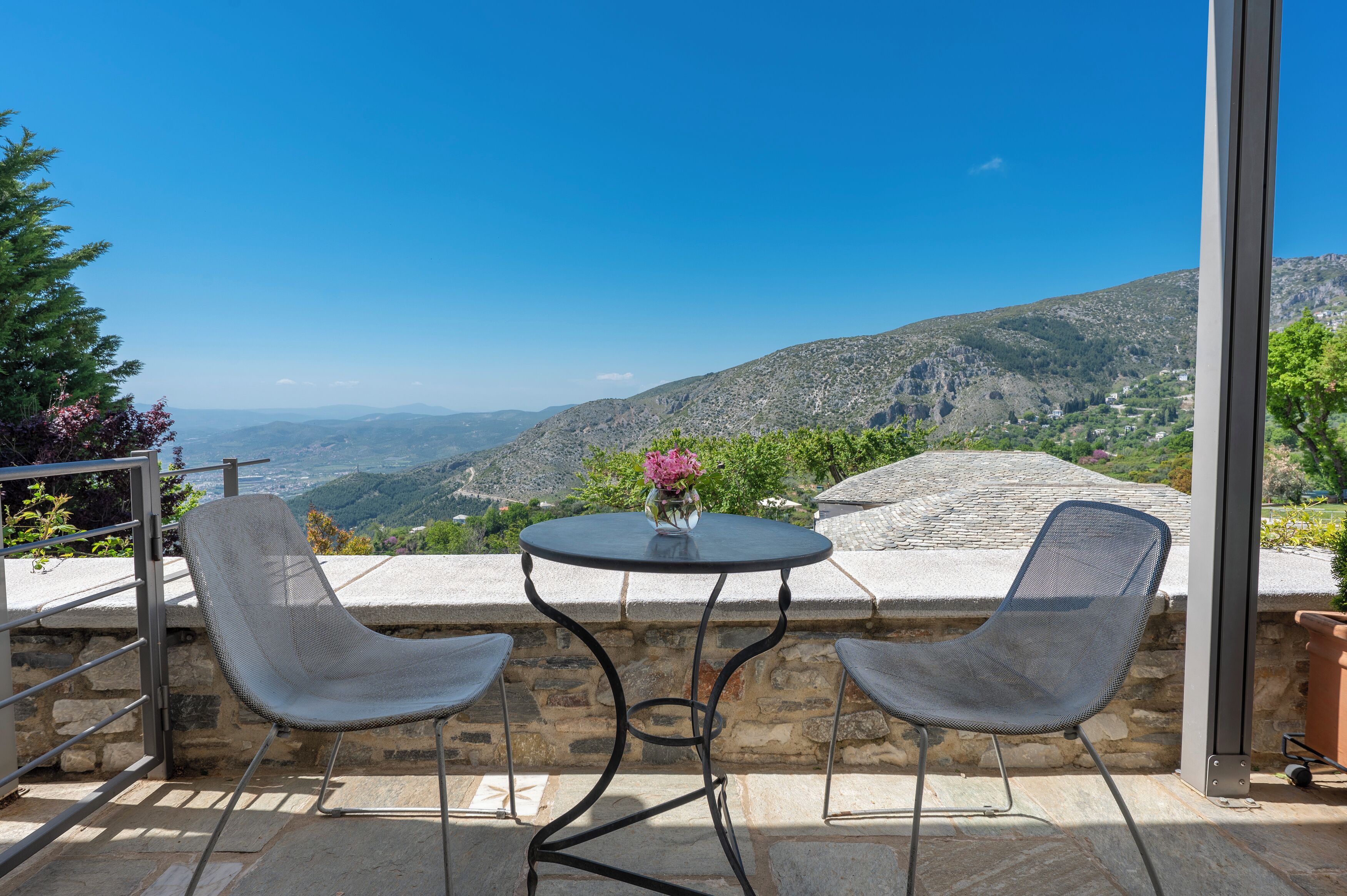 Un espacio de estar al aire libre con una mesa y dos sillas, con vistas a un paisaje montañoso.