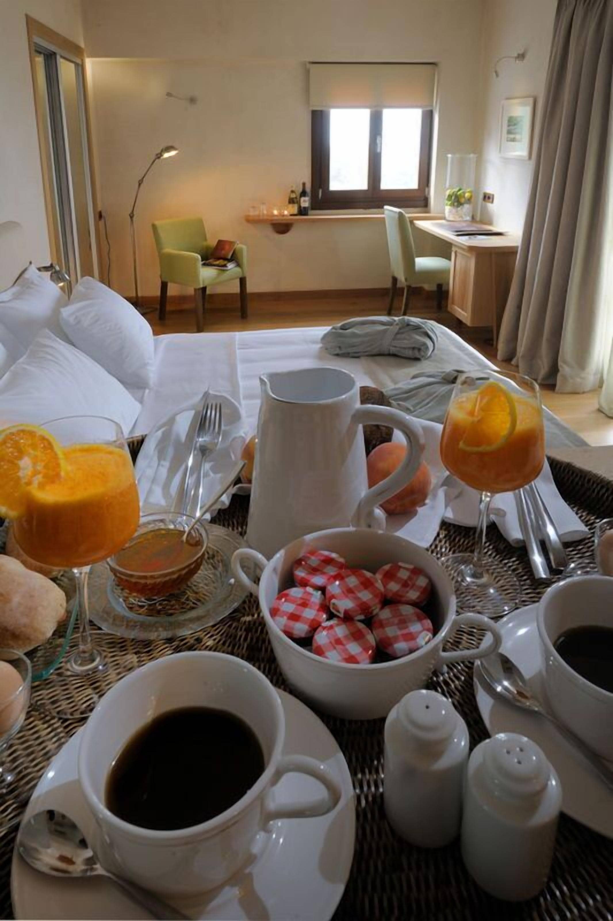 Una escena de desayuno con una cama, una mesa con provisiones para el desayuno, una silla y una ventana.
