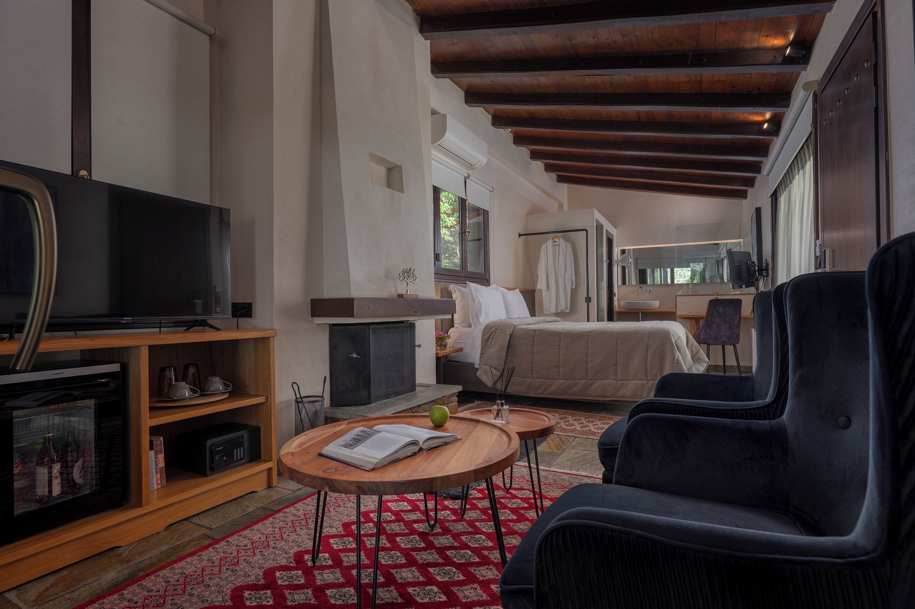 A modern hotel room with a television, a bed, a sofa, a small table, and a window.