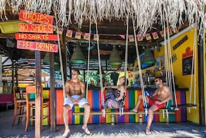 A bar with colorful seating and a sign indicating free drinks for ladies. - Mimosa Sunshine Hotel COOEE - All Inclusive (Golden Sands)