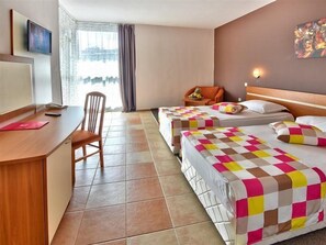 A hotel room with two beds, a desk, a chair, a TV, and a window with curtains. - Mimosa Sunshine Hotel COOEE - All Inclusive (Golden Sands)