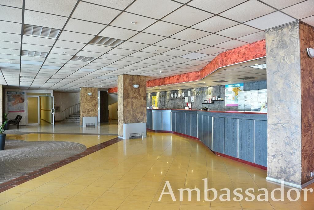 Een ruime lobby met een marmeren receptiebalie, een bordje met daarop 'Medisch Centrum' en een trap naar de hogere verdiepingen.