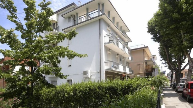 A multi-story residential building with balconies, surrounded by greenery and parked cars. - Hotel Ardesia (Rimini)