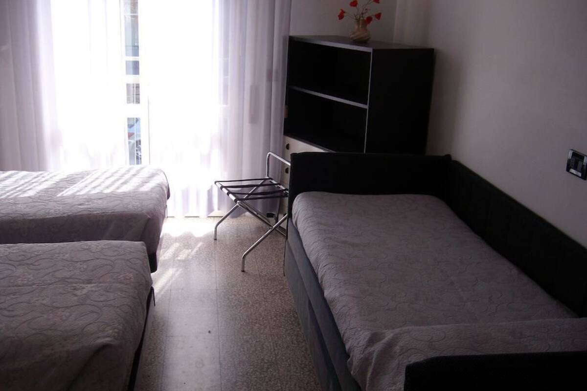 A hotel room with two beds, a small table, and a cabinet.