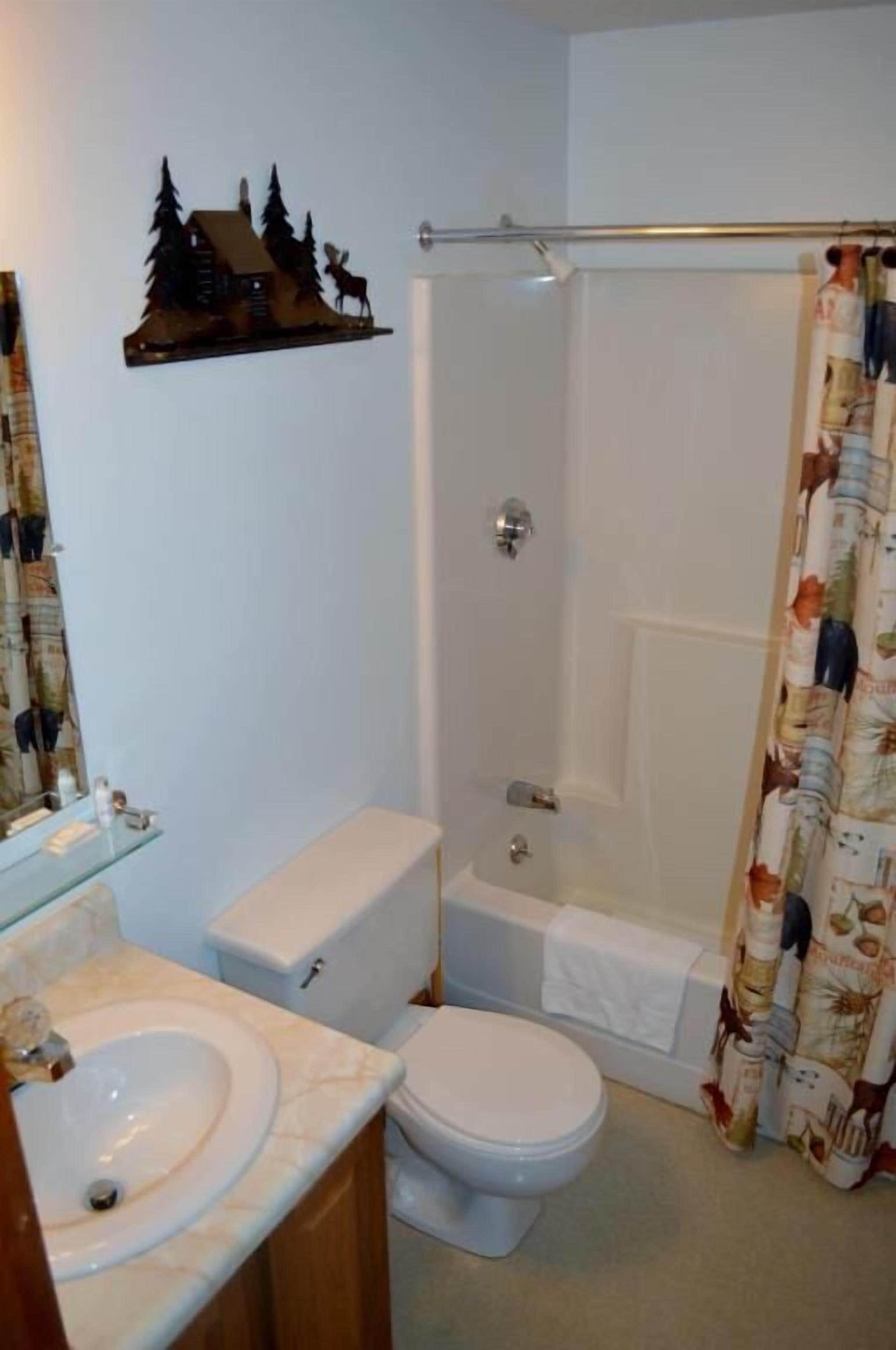 A bathroom with a toilet, sink, and shower.