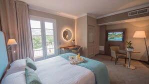 A hotel room with a bed, a desk, a chair, a TV, and a balcony with curtains. - Hôtel Lou Castelet (Carros)