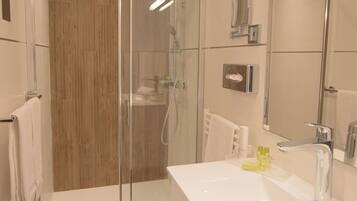 A modern bathroom with a glass-enclosed shower, a large white sink, and a mirror.