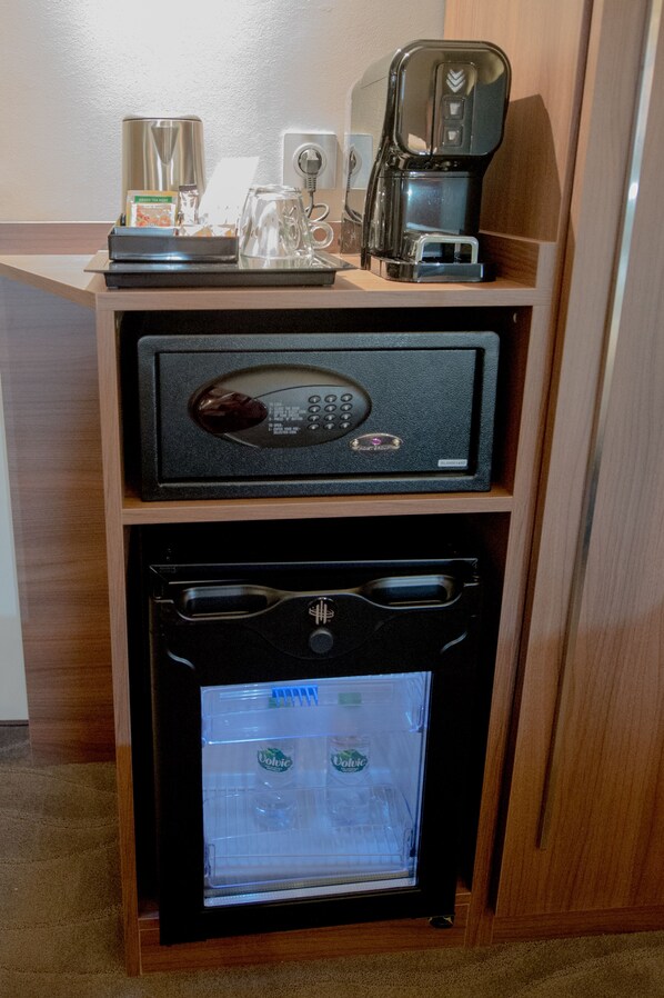 Una kitchenette compacta con microondas, cafetera y refrigerador.