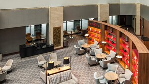 A hotel lobby with multiple seating areas, a reception desk, and a bar area with shelves. - Crowne Plaza London Heathrow T4 by IHG (Hounslow)