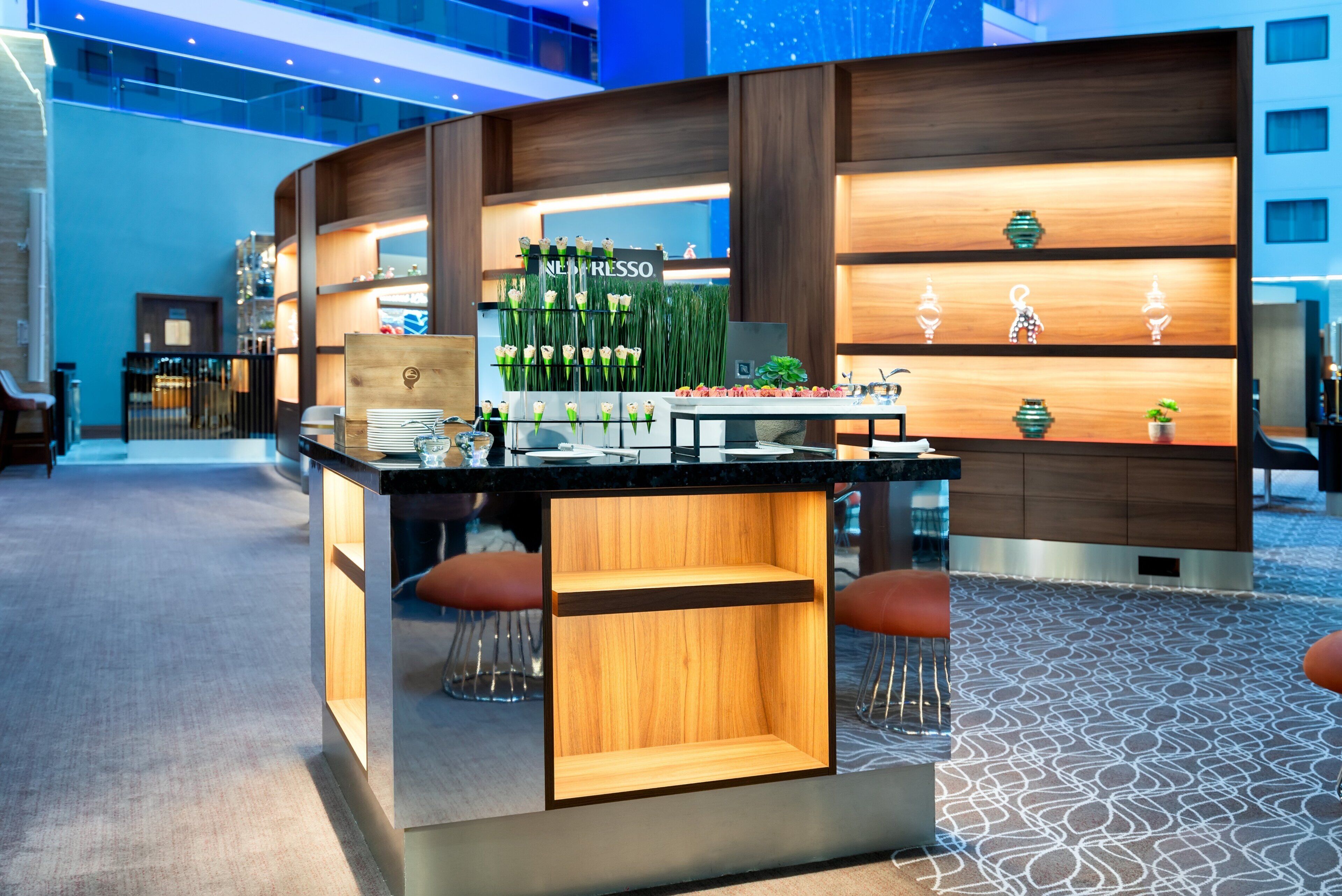A modern bar area with a wooden counter, seating, and a display of espresso cups.