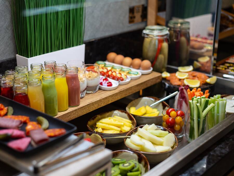 A buffet with various food items including fruits, vegetables, and beverages.