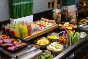 Un bufé con diversas opciones de comida, incluyendo frutas, verduras y bebidas.