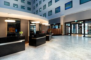 A hotel reception area with a curved reception desk, a large window, and a modern interior design. - Crowne Plaza London Heathrow T4 by IHG (Hounslow)