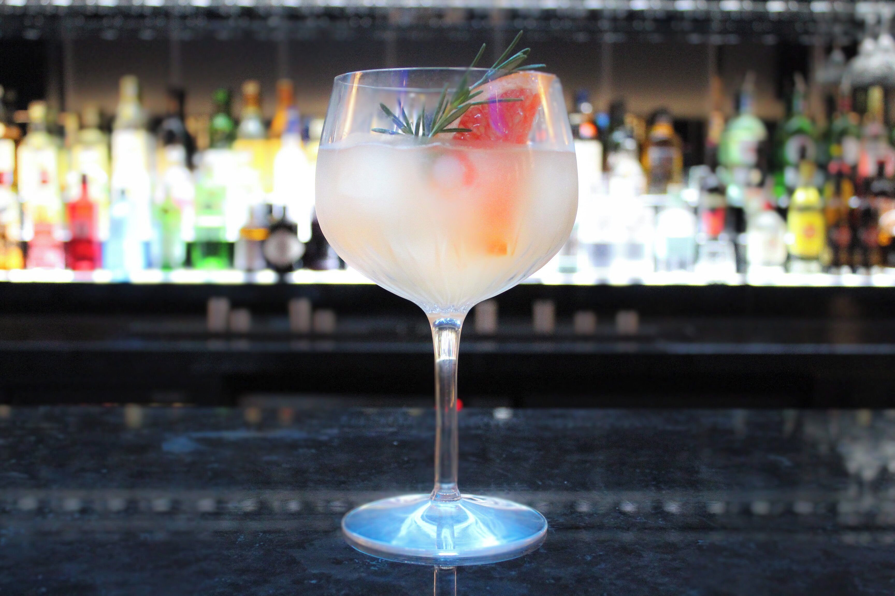 Un verre à cocktail rempli de glaçons et agrémenté d’une garniture, posé sur le comptoir d’un bar.