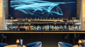 A bar area with a digital light installation, a variety of liquor bottles, and bar stools. - Crowne Plaza London Heathrow T4 by IHG (Hounslow)