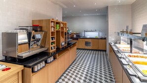 A modern self-service breakfast area with a coffee machine, a variety of mugs, and a buffet with various food items. - Holiday Inn Express London Heathrow T4 by IHG (Hounslow)