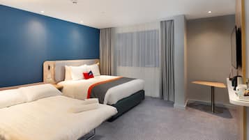 A hotel room with two beds, a desk, a chair, a TV, and a window with curtains.