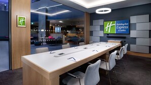 A modern conference room with a long table, chairs, and a large screen displaying the Holiday Inn Express logo. - Holiday Inn Express London Heathrow T4 by IHG (Hounslow)