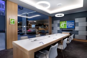 A modern conference room with a long table, chairs, and a large screen displaying the Holiday Inn Express logo.