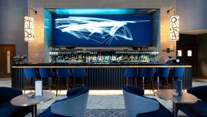 A bar area with a modern design, featuring a long counter, multiple bar stools, and a large screen displaying abstract art. - Holiday Inn Express London Heathrow T4 by IHG (Hounslow)