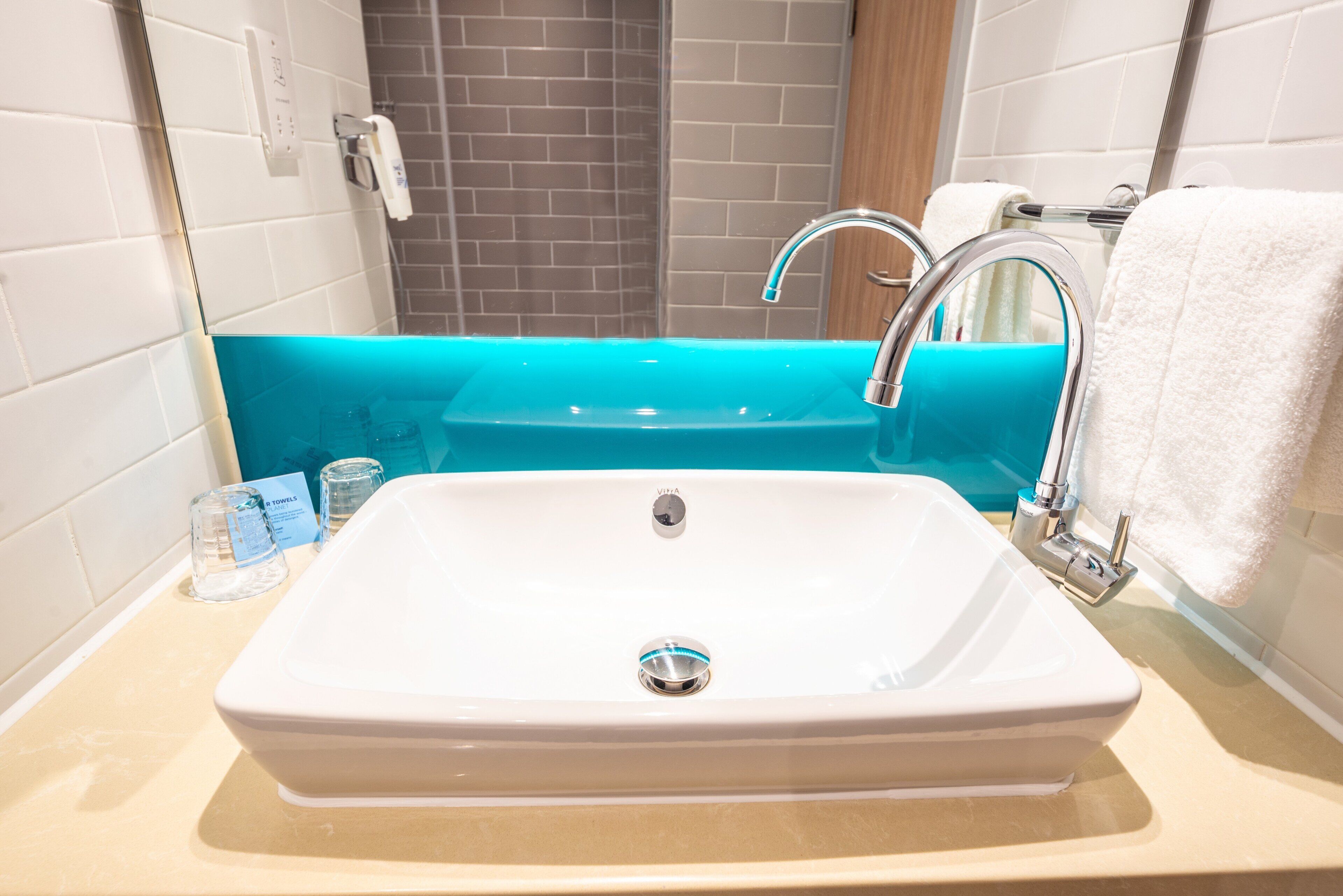 A bathroom with a white sink, a turquoise bathtub, and a white towel hanging on the wall.