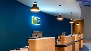 A hotel reception area with multiple wooden reception desks, a blue wall with a starry ceiling design, and a sign for the Holiday Inn Express & Suites. - Holiday Inn Express London Heathrow T4 by IHG (Hounslow)