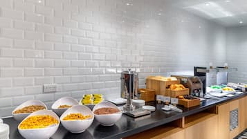 A buffet setup with various food items and a coffee machine.