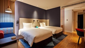 Een hotelkamer met twee bedden, een bureau, een stoel en een bank.