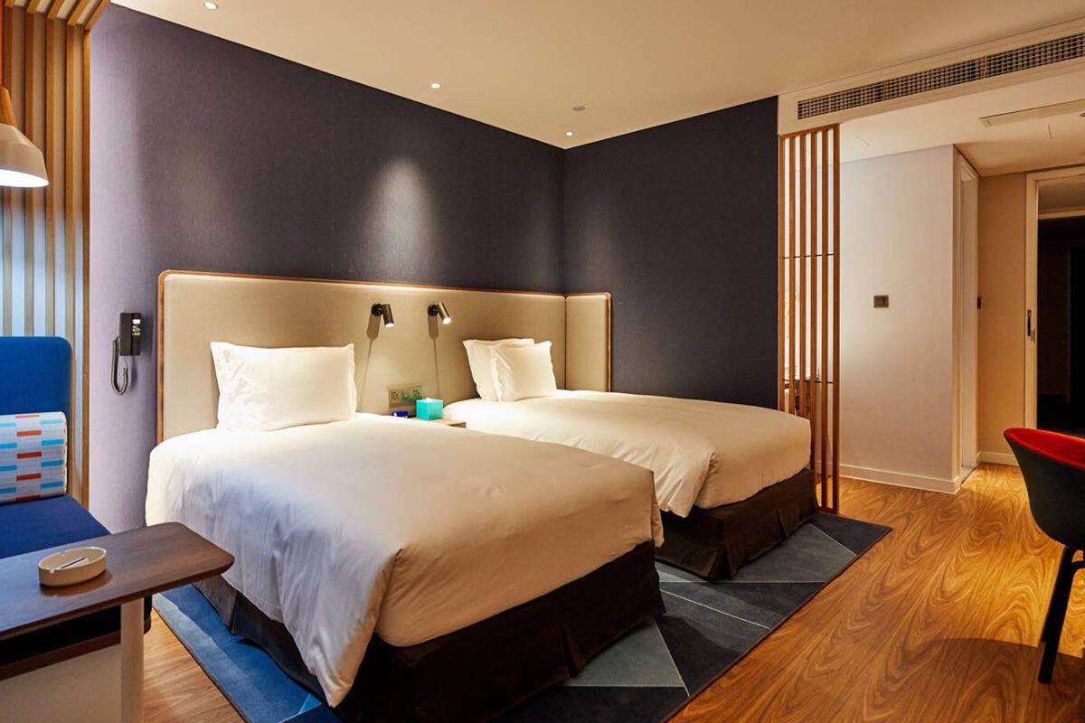 Une chambre d’hôtel avec deux lits, un bureau, une chaise et un canapé.