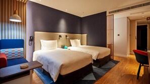 A hotel room with two beds, a desk, a chair, and a sofa.