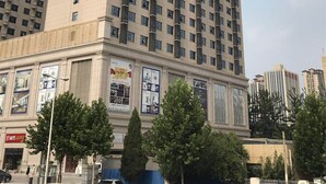 Un grand hôtel, un immeuble de grande hauteur avec de nombreux étages, et une enseigne verte bien visible sur le côté.
