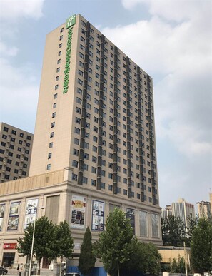 Un grand hôtel, un immeuble de grande hauteur avec de nombreux étages, et une enseigne verte bien visible sur le côté.