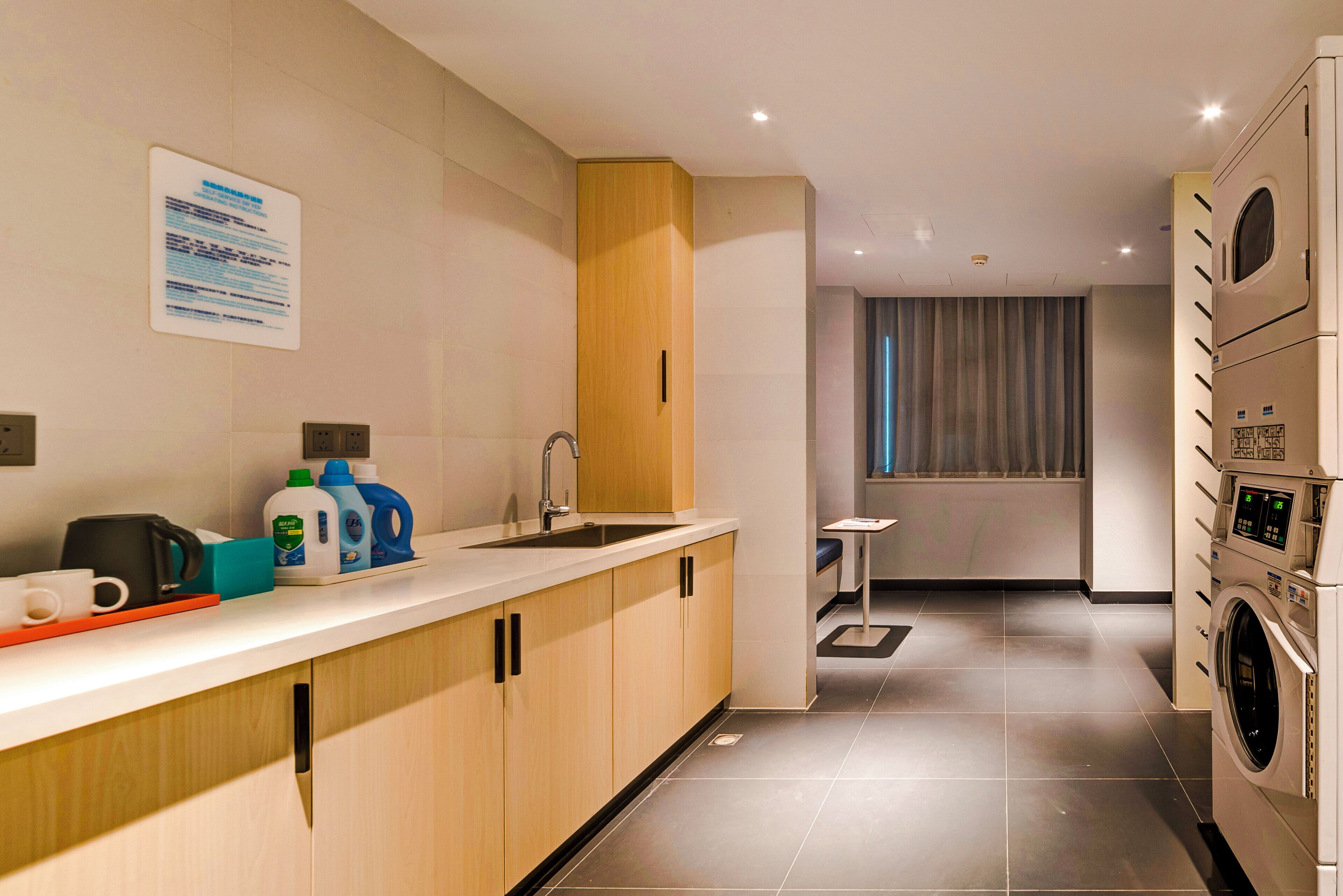 A modern kitchen with a built-in washing machine, a coffee machine, and a small table.