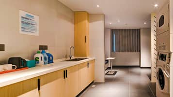 A modern kitchen with a built-in washing machine, a coffee machine, and a small table.