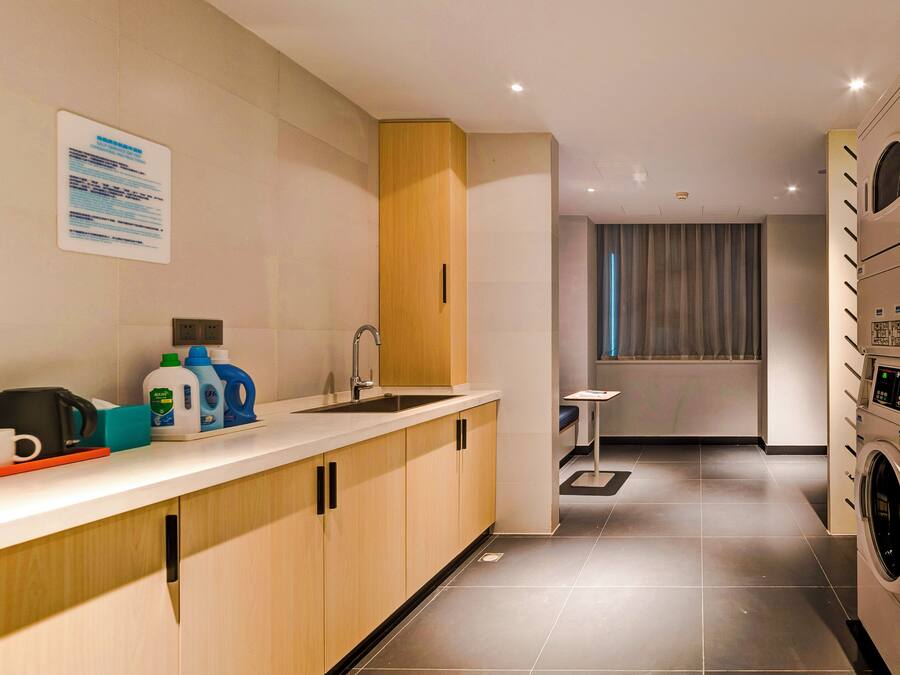 A modern kitchen with a built-in washing machine, a coffee machine, and a small table.