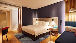 Een moderne hotelkamer met een groot bed, nachtkastjes, een bureau en een stoel.