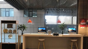 Un comptoir d’accueil moderne, doté de deux écrans, d’une imprimante et d’une vitrine en verre où sont exposés des trophées.