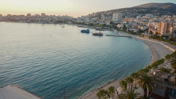 A coastal cityscape with a beach, boats, and buildings. - Serxhio Apartments (Sarandë)