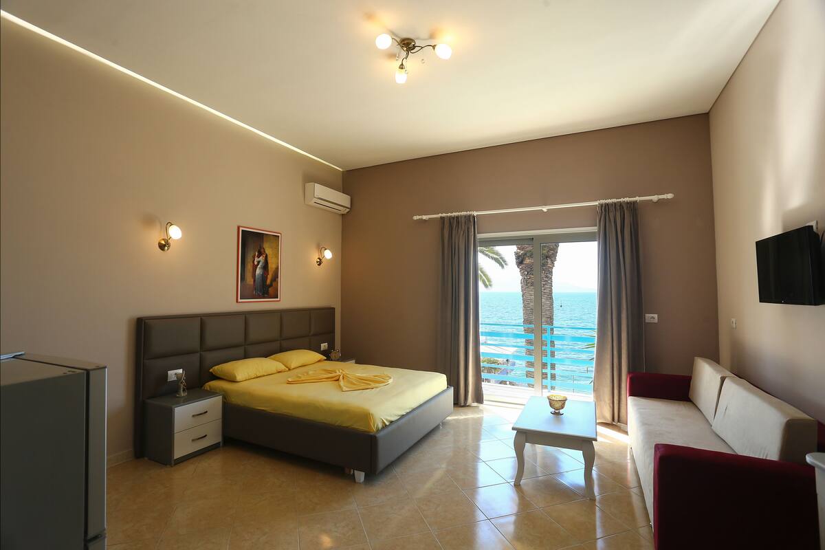 A bedroom with a bed, bedside table, and a view of the ocean.
