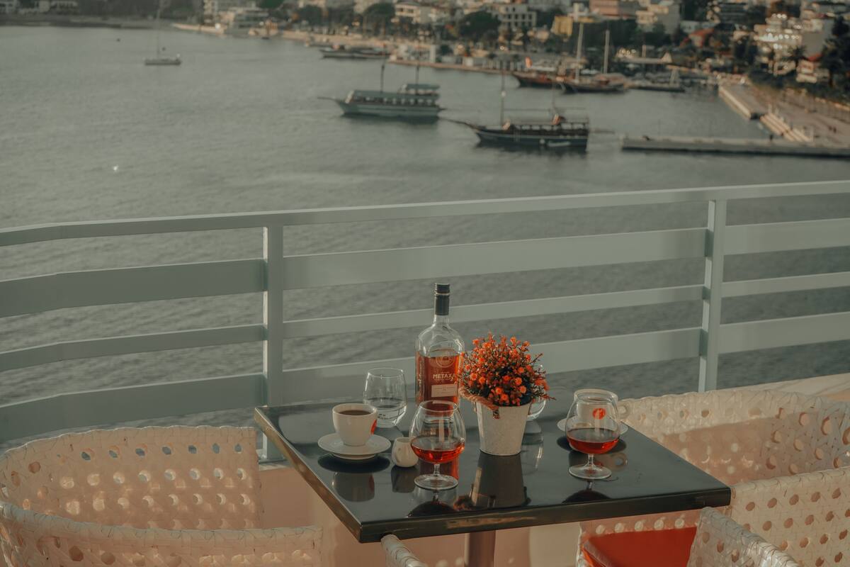 A balcony with a table set for two, overlooking a marina with boats.