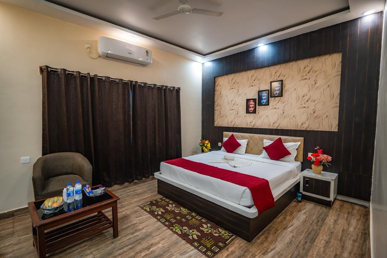 A modern hotel room with a large bed, a small table with toiletries, a chair, and a decorative wall panel.