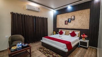 A modern hotel room with a large bed, a small table with toiletries, a chair, and a decorative wall panel.