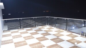 Een terras op het dak met een geruit vloermozaïek en glazen hekwerk.