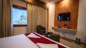 Een hotelkamer met een bed, een bureau, een stoel, een televisie en uitzicht op een gebouw.