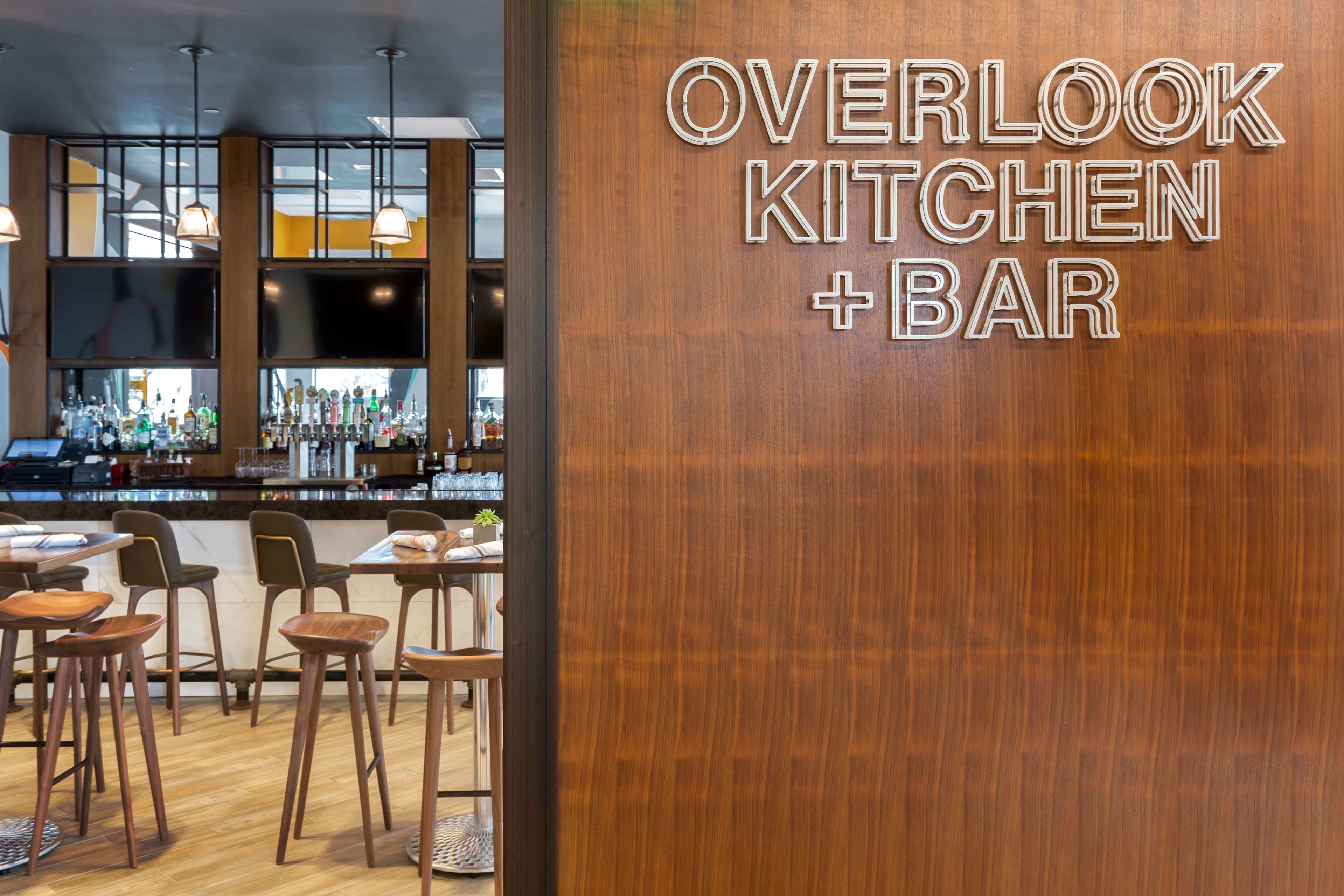 A restaurant interior with a bar area, wooden furniture, and a large window.