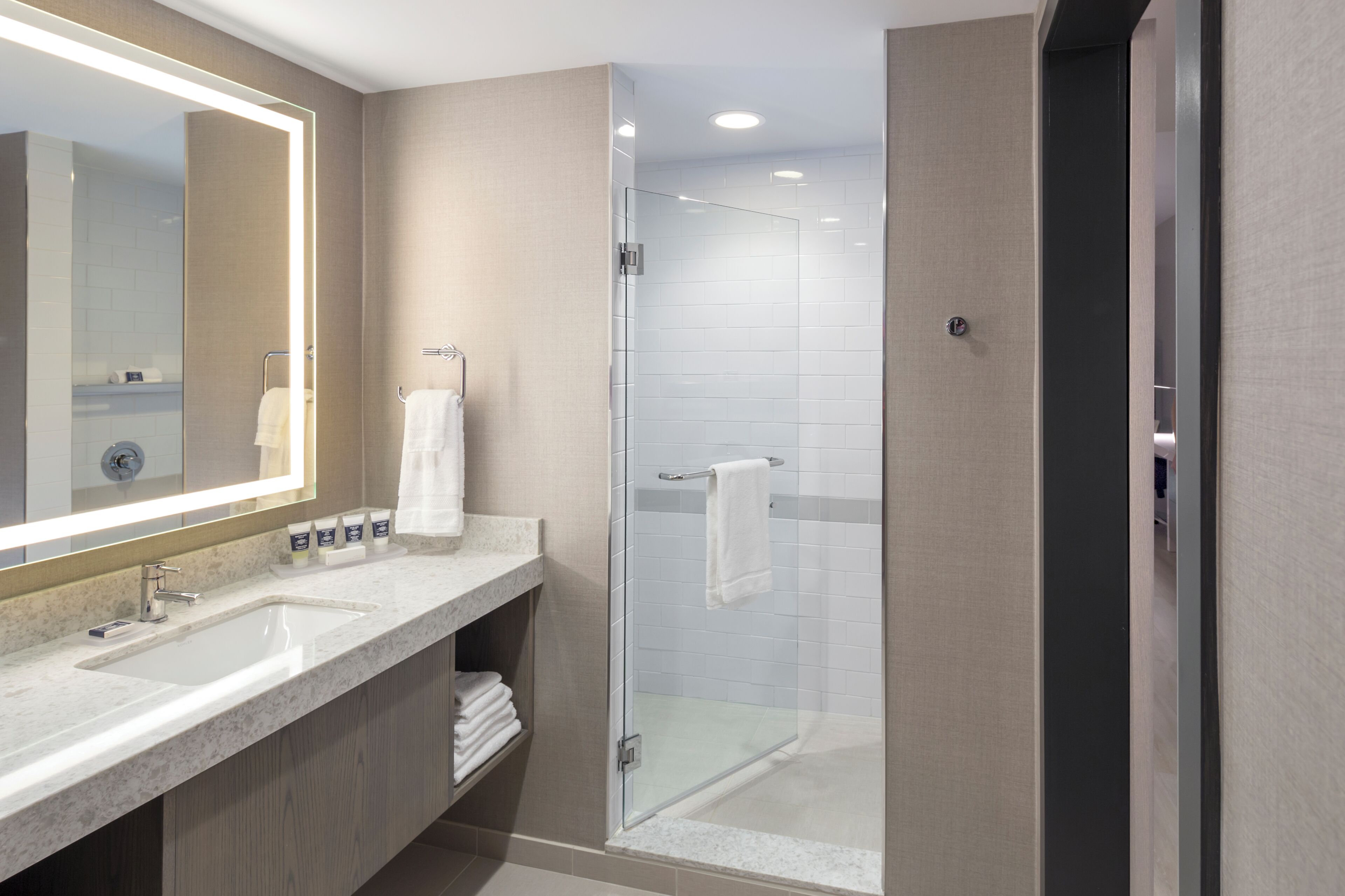 Un baño moderno con dos lavamanos, una cabina de ducha de cristal y un espejo grande.