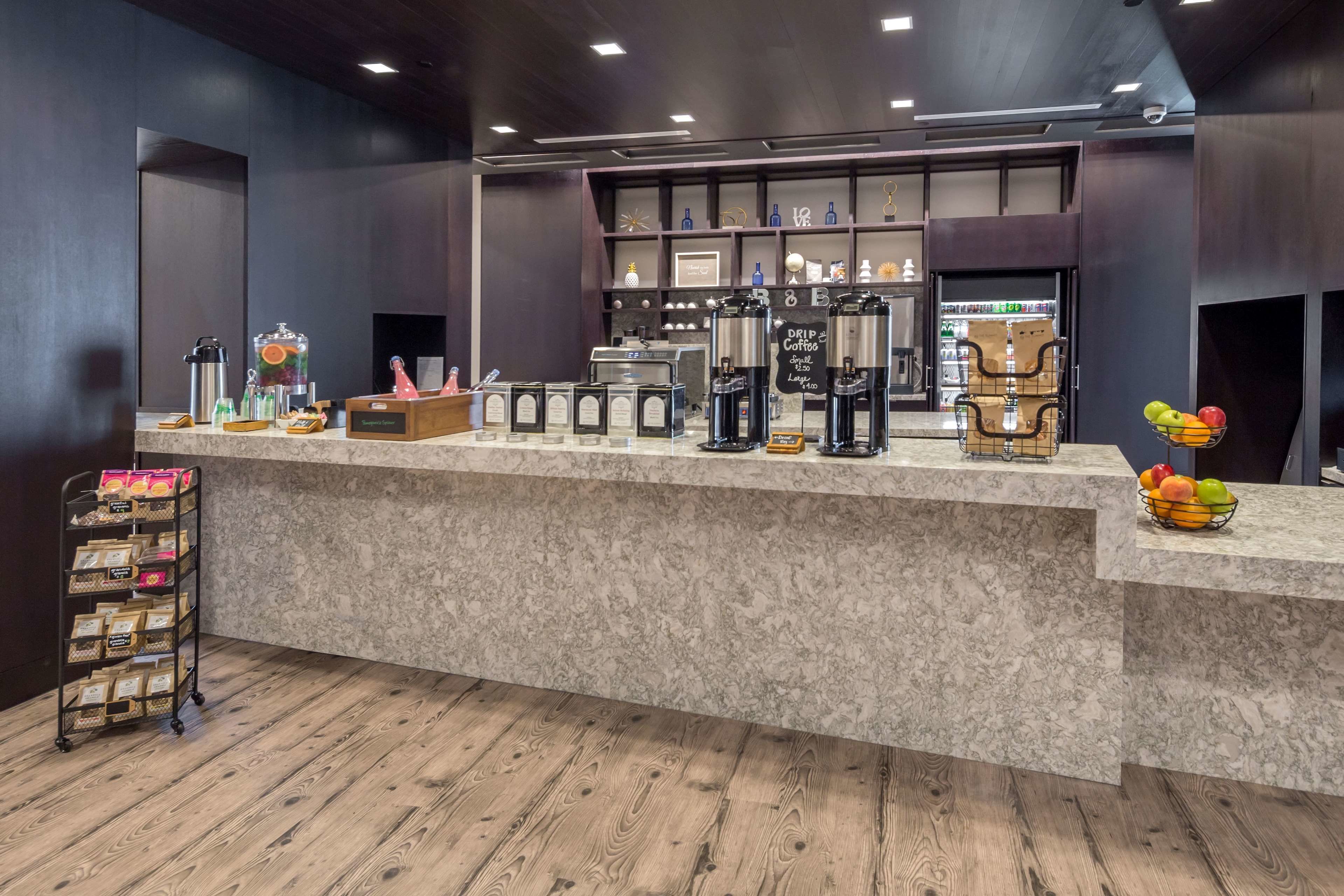 A coffee station with a marble counter, coffee machines, and a fruit basket.