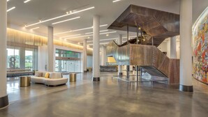 A spacious lobby with a modern staircase, a seating area, and a large abstract painting. - The Summit Hotel (Cincinnati)